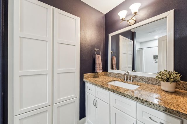 a bathroom with a granite countertop sink and a mirror
