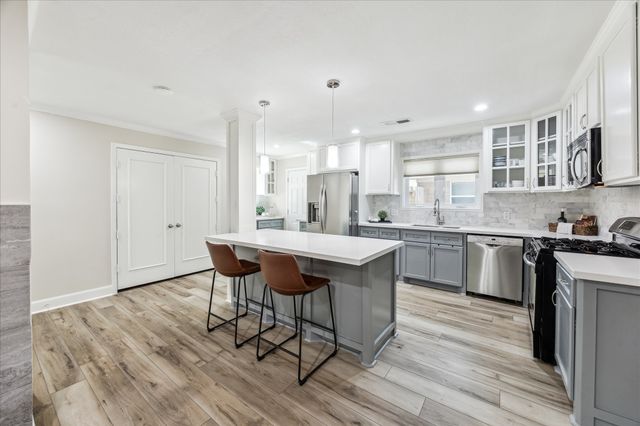 a kitchen with stainless steel appliances granite countertop a table chairs sink refrigerator and cabinets