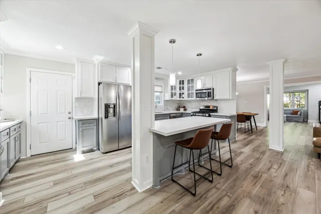 a kitchen with stainless steel appliances a dining table chairs refrigerator and sink