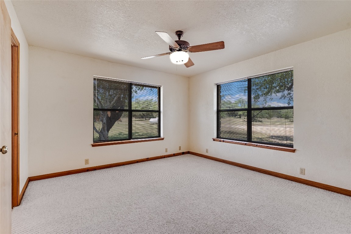 199 Middleton Road Spicewood, TX 78669 - Photo 21 of 39 an empty room with windows and ceiling fan