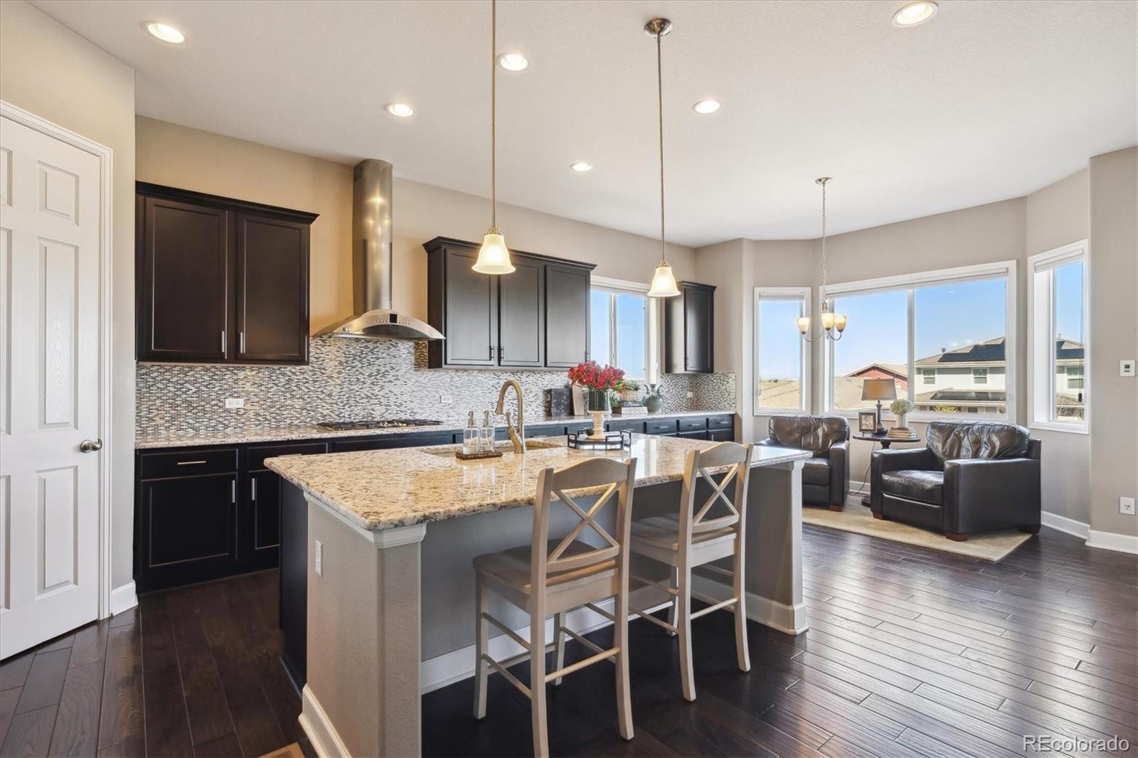 14100 Sierra Ridge Circle Parker, CO 80134 - Photo 9 of 37 a kitchen with stainless steel appliances granite countertop a stove a sink refrigerator and a dining table with wooden floor