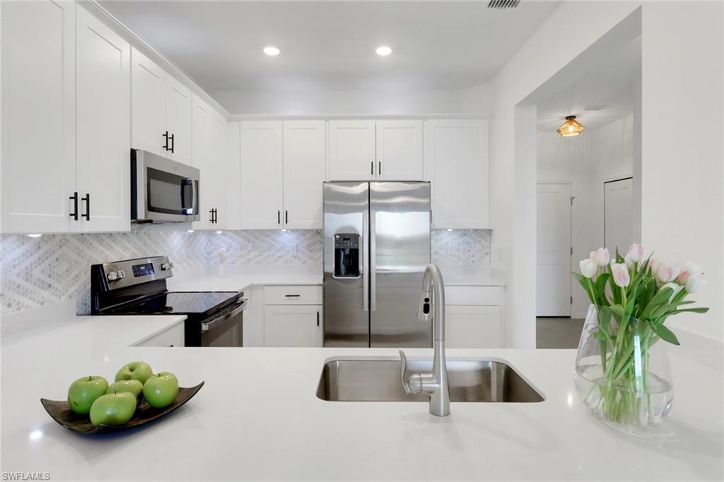 a kitchen with stainless steel appliances a sink a microwave a refrigerator and a counter top space