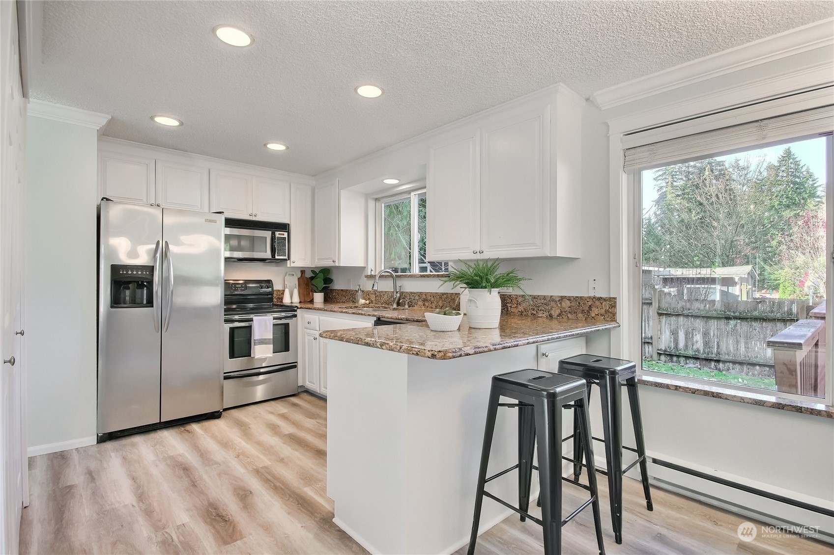 19818 34th Drive Southeast Bothell, WA 98012 - Photo 12 of 34 a kitchen with stainless steel appliances granite countertop a stove a refrigerator a sink a stove and white cabinets with wooden floor