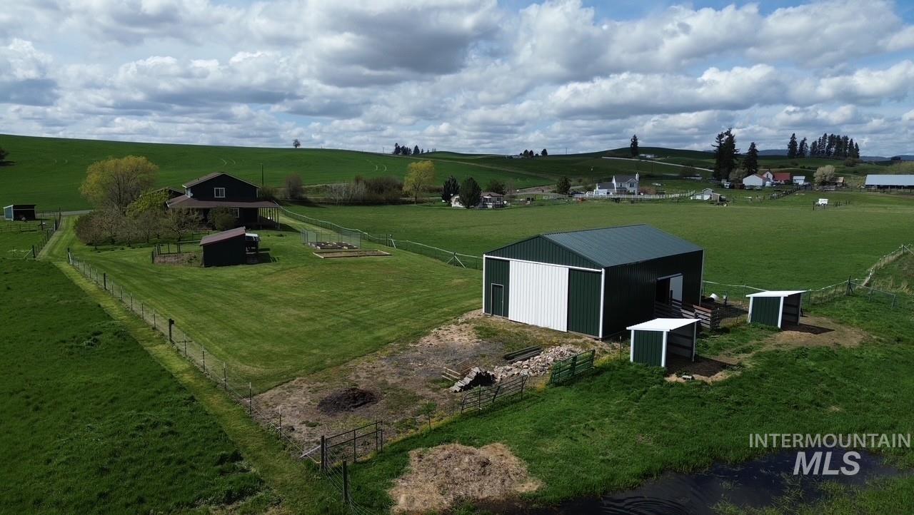 1277 Kennedy Ford Road Potlatch, ID 83855 - Photo 42 of 48 Expansive property featuring a dark-toned residence, a large green and white metal outbuilding, multiple smaller auxiliary structures, and fenced boundaries