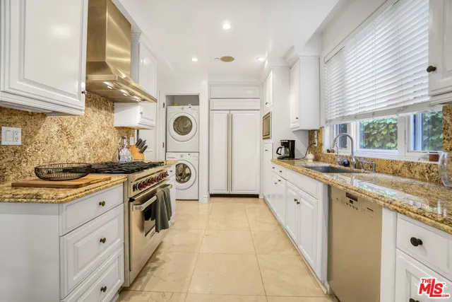 a large kitchen with stainless steel appliances granite countertop a stove a sink and white cabinets
