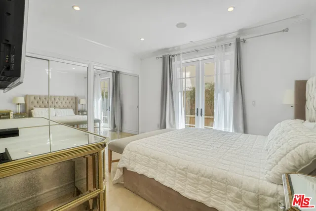 a spacious bedroom with a bed and a flat screen tv