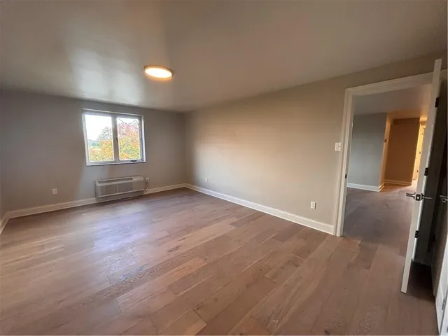an empty room with wooden floor and window