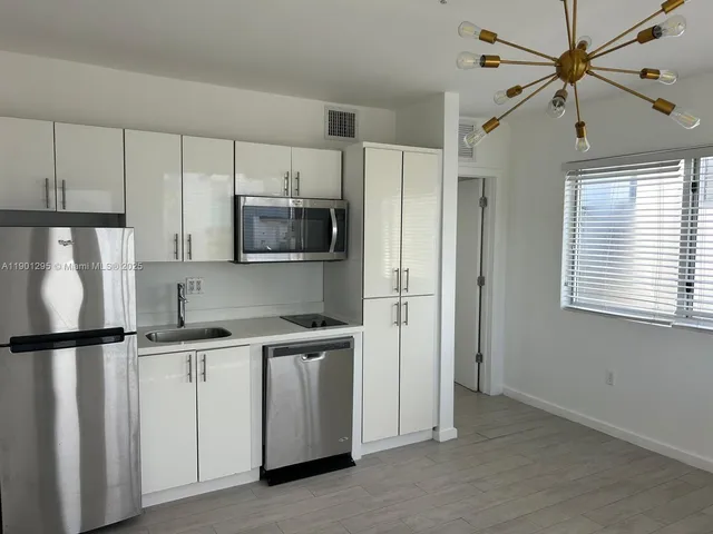 a kitchen with white cabinets and black appliances