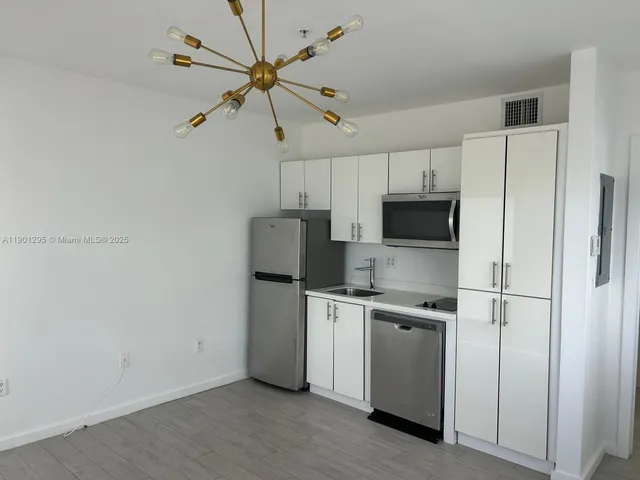 a kitchen with stainless steel appliances a refrigerator a stove a microwave and white cabinets