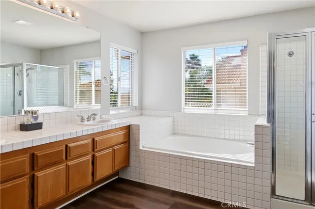 a bathroom with double vanity sink a two mirror a window and a bathtub