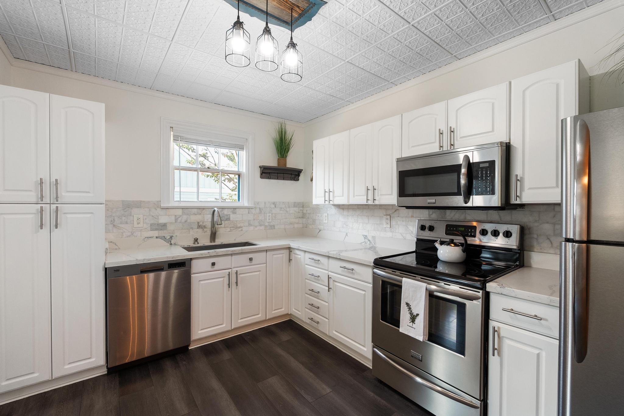 1707 Lexington Street Taylor, TX 76574 - Photo 11 of 29 Kitchen featuring stainless steel appliances, white cabinets, dark wood-type flooring, and ornamental molding