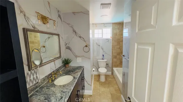 a bathroom with a granite countertop sink toilet and shower