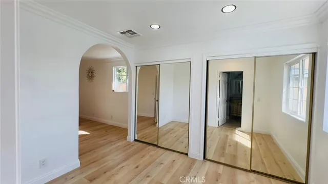 an empty room with wooden floor mirror and windows