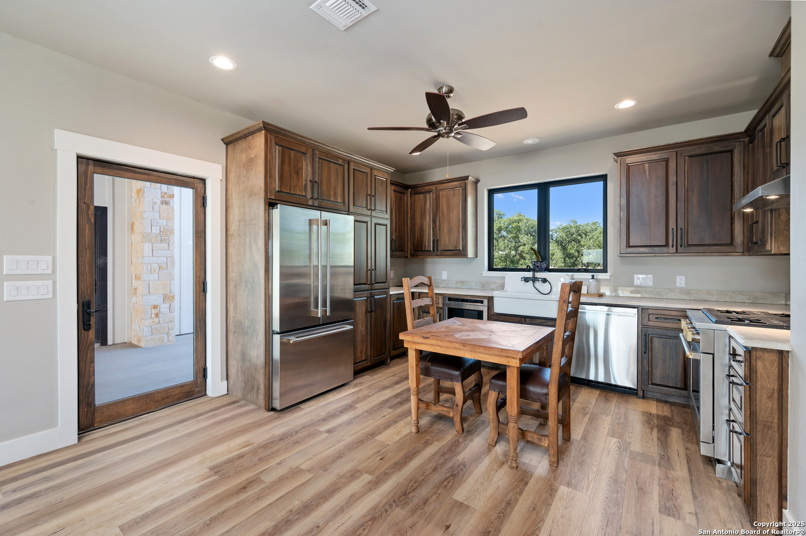 235 Sattler Road Spring Branch, TX 78070 - Photo 30 of 43 a kitchen with stainless steel appliances granite countertop a refrigerator oven a sink dishwasher a dining table and chairs with wooden floor