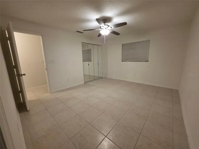 an empty room with windows and fan