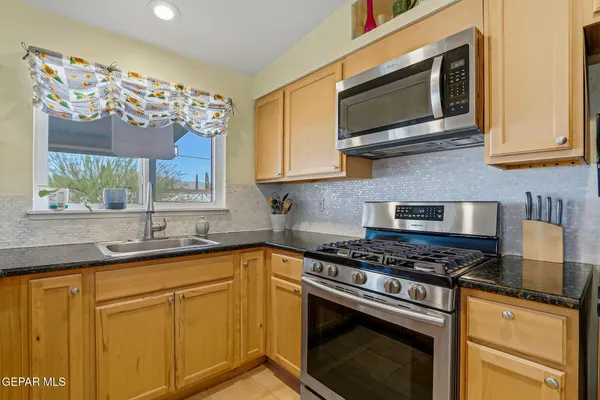 a kitchen with stainless steel appliances granite countertop a stove microwave and sink