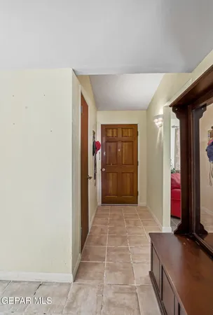 a view of hallway with a refrigerator and mirror