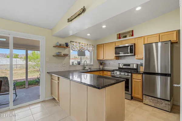 a kitchen with stainless steel appliances granite countertop a refrigerator a stove a sink a dining table and chairs