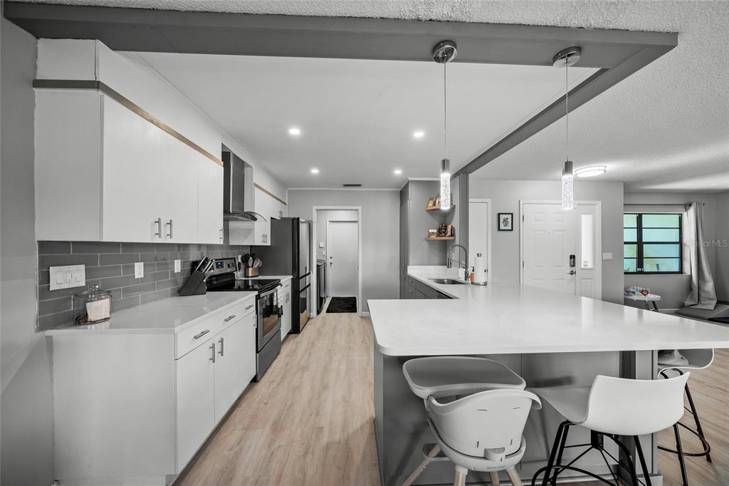 3020 Gypsy Street Sarasota, FL 34231 - Photo 6 of 34 a large kitchen with kitchen island a dining table chairs stainless steel appliances and cabinets