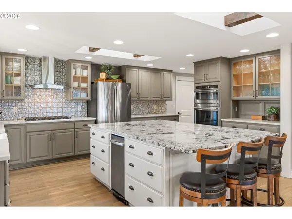 a kitchen with stainless steel appliances kitchen island granite countertop a refrigerator and cabinets