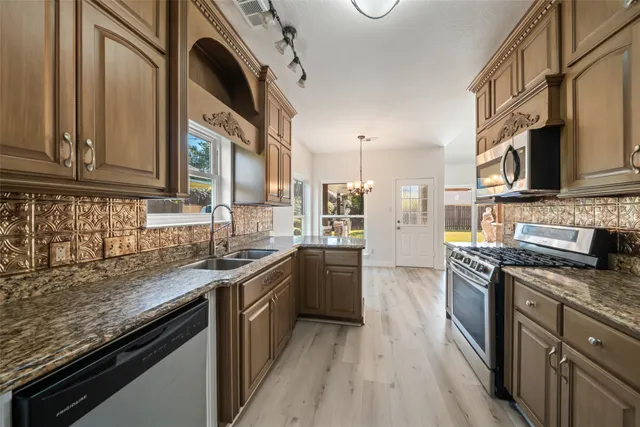 a kitchen with stainless steel appliances granite countertop a sink a stove oven and cabinets