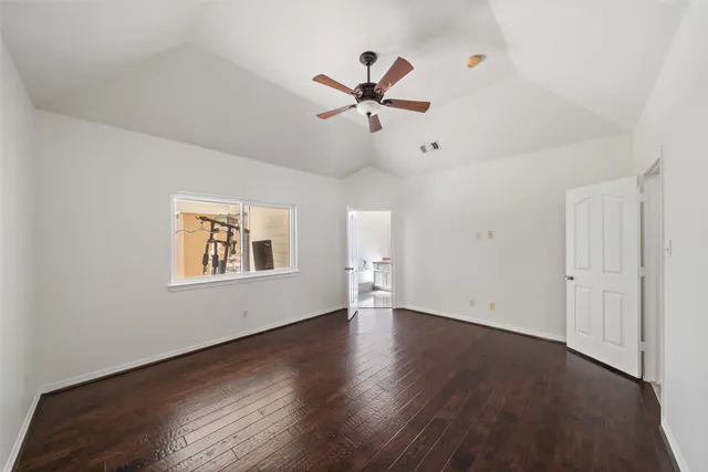 an empty room with wooden floor ceiling fan and windows