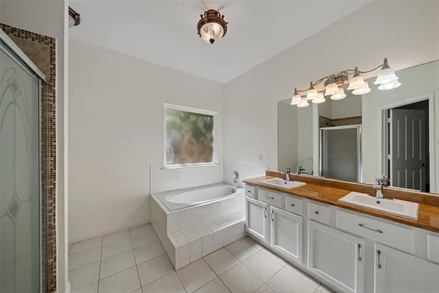 a spacious bathroom with a granite countertop double vanity sink a mirror a and a bathtub