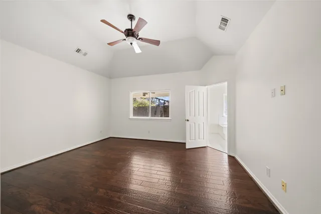 an empty room with wooden floor ceiling fan and windows