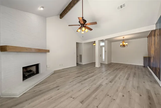 a view of a livingroom with a fireplace a ceiling fan and wooden floor