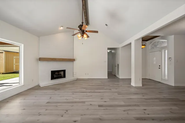 a view of an empty room with a fireplace and a window