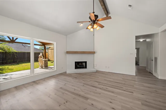 a view of an empty room with a fireplace and a window