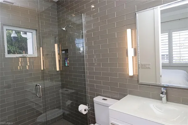 a bathroom with a sink a toilet a mirror and shower