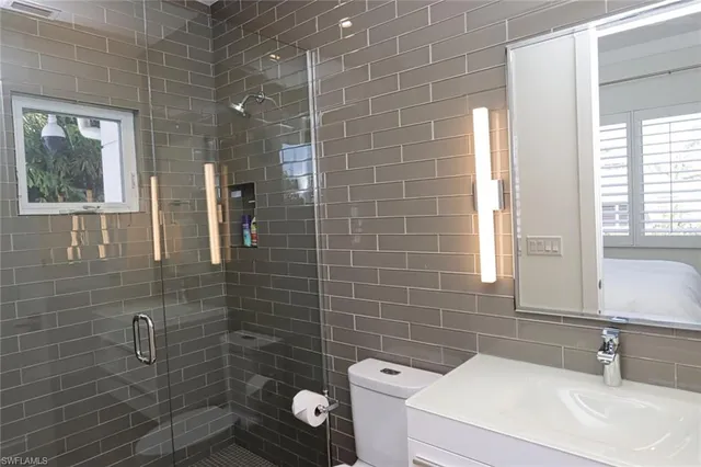 a bathroom with a sink a toilet a mirror and shower