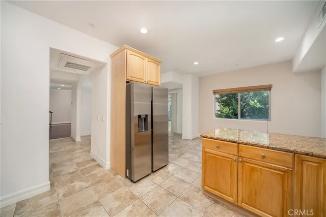 a view of a refrigerator in kitchen and wooden cabinets