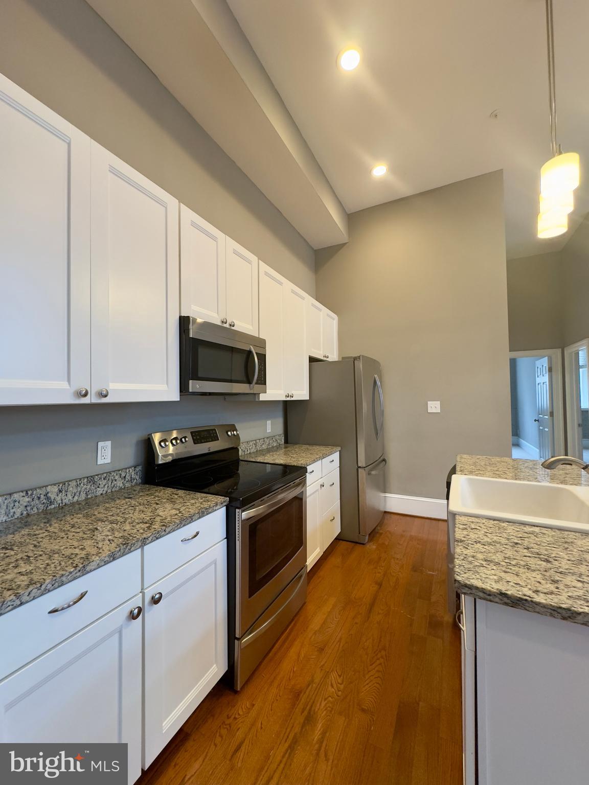 7 West Mulberry Street, Unit 7 Baltimore, MD 21201 - Photo 12 of 16 a kitchen with granite countertop a sink a stove top oven and cabinetry
