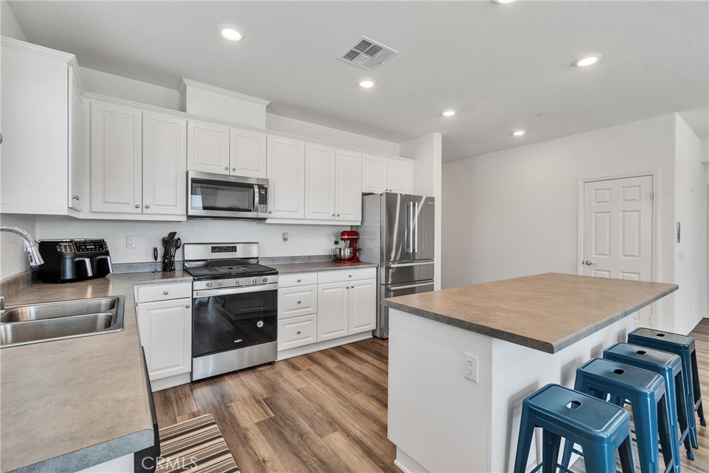 402 Appleton Way Perris, CA 92570 - Photo 28 of 34 a kitchen with kitchen island a sink dishwasher a stove a refrigerator and a stove with wooden floor