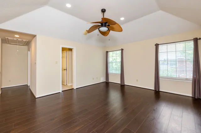 a view of an empty room with wooden floor and window