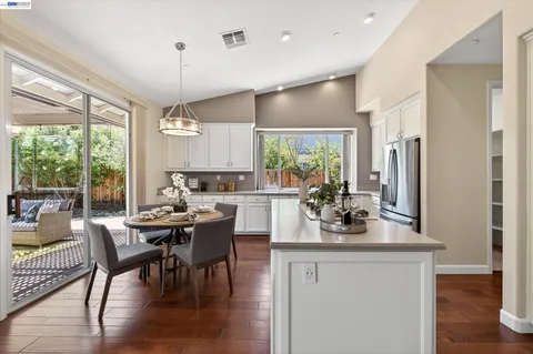 a kitchen with stainless steel appliances a dining table chairs stove refrigerator and cabinets