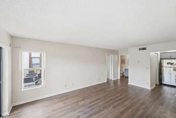 a view of an empty room with wooden floor and a window