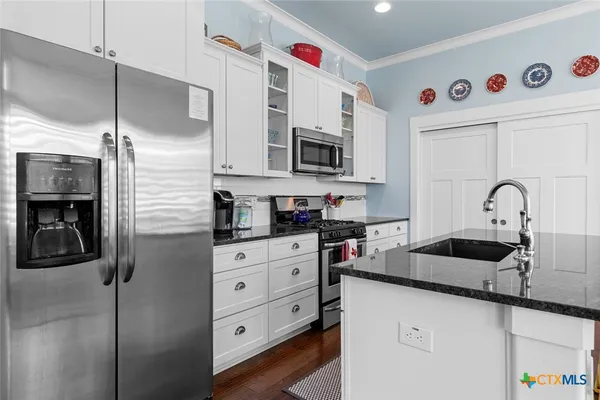 a kitchen with stainless steel appliances granite countertop a sink and a refrigerator