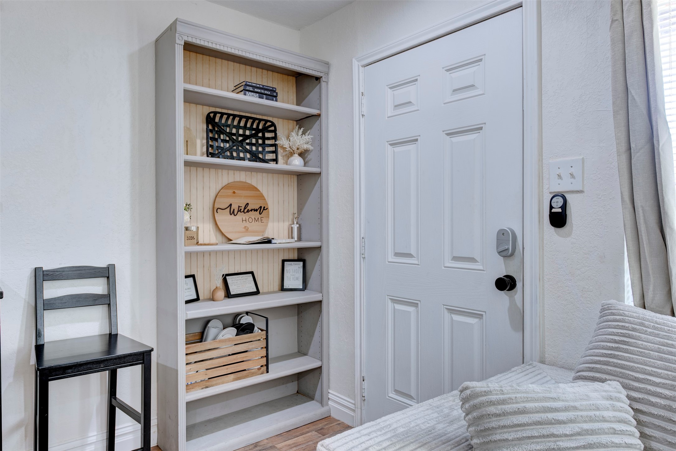1121 Panama Street Houston, TX 77009 - Photo 4 of 35 Entryway featuring white six-panel door with smart lock and black lever hardware, built-in five-shelf bookcase with natural pine beadboard back panel, wood-look LVP flooring, and oversized window with natural light.