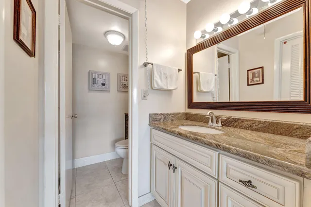 a bathroom with a granite countertop sink mirror and a toilet