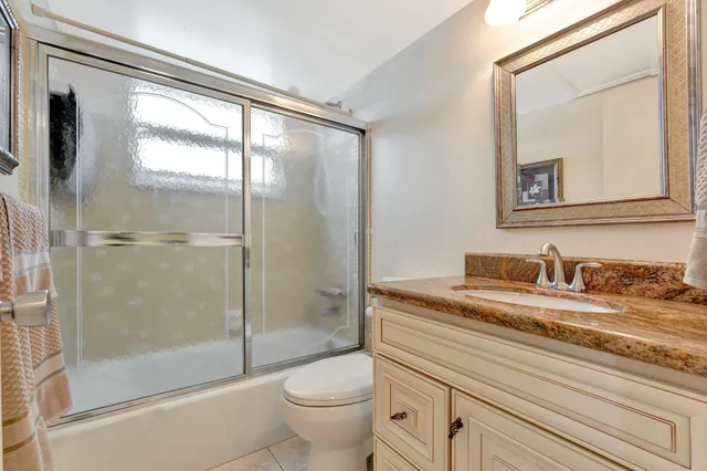 a bathroom with a granite countertop sink mirror vanity and toilet