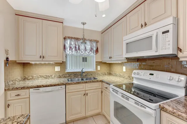 a kitchen with granite countertop white cabinets and white appliances