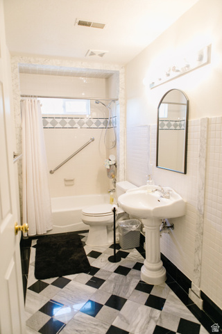 104 South Ridgeview Drive Orem, UT 84058 - Photo 32 of 49 Bathroom featuring a black and white checkered marble floor, a pedestal sink, a bathtub with a tiled surround, a built-in grab bar, and a wall-mounted light fixture