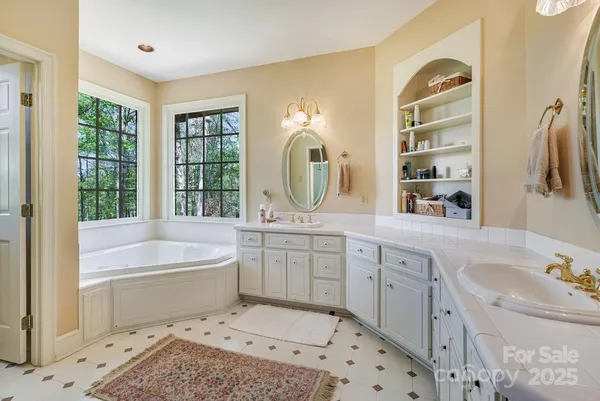 a spacious bathroom with a tub sink and mirror