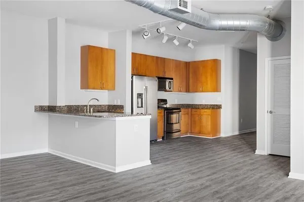 a kitchen with stainless steel appliances granite countertop a sink a stove a refrigerator cabinets and wooden floor