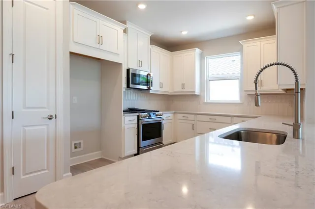 a kitchen with granite countertop a stove a sink and a refrigerator