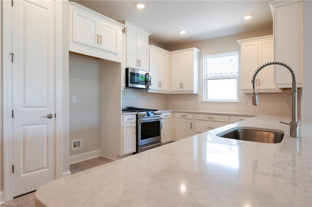 15633 Gavello Street Naples, FL 34114 - Photo 17 of 37 a kitchen with granite countertop a stove a sink and a refrigerator