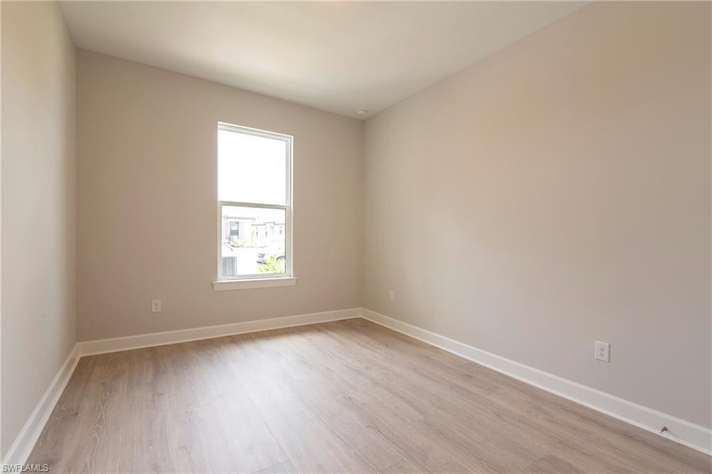 15633 Gavello Street Naples, FL 34114 - Photo 23 of 37 an empty room with wooden floor and windows